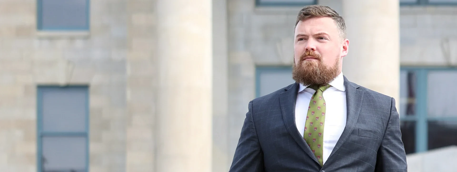 Landon Miller standing confidently in front of a courthouse wearing a suit and tie
